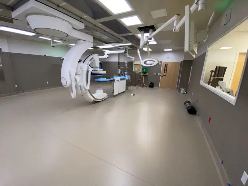 A spacious and well-lit medical operating room in North Las Vegas with advanced equipment, including large overhead machinery and computer monitors, all supported by reliable electric service from Adamik Electric.