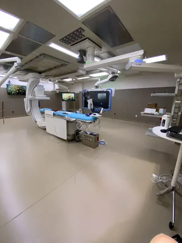 A hospital operating room in North Las Vegas with medical equipment, monitors, and an examination table. The room is modern with overhead lights and various devices positioned around, all expertly maintained by Adamik Electric's top-notch electric service.